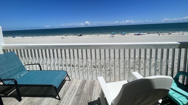 A beach view from a balcony with two lounge chairs and a wooden deck. - Beach Front Property with Stunning  Ocean Front View in the Ocean Dunes Resort (Kure Beach)