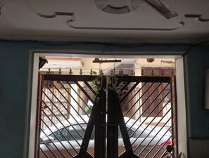 Vista a través de una reja metálica, con un automóvil estacionado afuera.