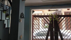 A room with a blue wall, a ceiling fan, and a window with a metal gate. - An independent floor, with one bedroom, kitchen, (Gurugram)