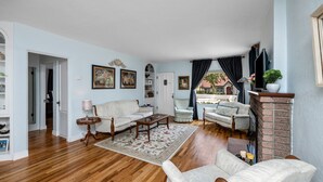 A spacious living room with hardwood floors, a fireplace, and a view of a brick wall. - Charming Home in Prescotts Historic District. Less than a mile from Whiskey Row. (Prescott)