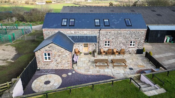 A stone building with a sloped roof, outdoor seating area, and a paved patio.