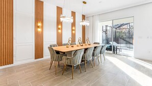 Un comedor moderno con una mesa de madera y sillas tapizadas de color gris, ventanas amplias y vistas al exterior.