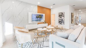 Un moderno salón con pared de mármol, un televisor de pantalla plana grande, un panel de madera y arte abstracto.