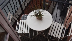 A round table with a potted plant, surrounded by white chairs on a wooden deck. - Scandinavian City Centre Apartment (Worcester)