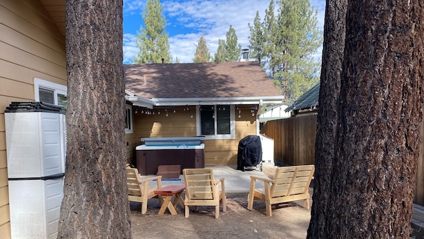 Un jardin avec un jacuzzi, des chaises en bois et un barbecue.