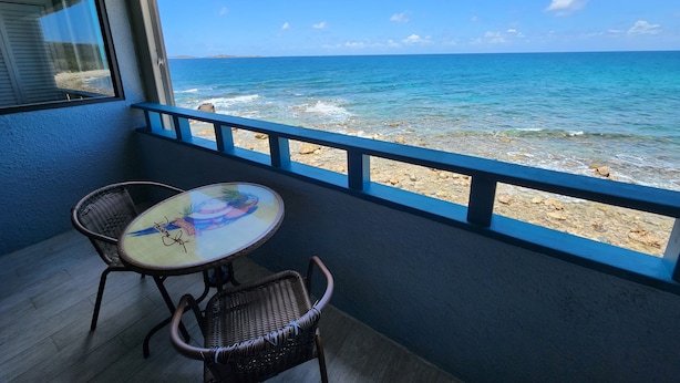 Un balcon avec une table et des chaises donnant sur une plage.