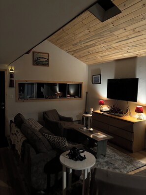 Una sala de estar con sofá, mesa de centro, televisor y chimenea.
