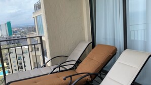 Un balcon agrémenté de deux fauteuils de relaxation, l’un avec un coussin marron et l’autre avec un coussin blanc, d’où l’on peut admirer la vue sur la ville.