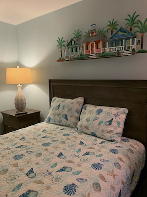 Une chambre à coucher avec un lit, une table de chevet, une lampe et un élément décoratif mural.