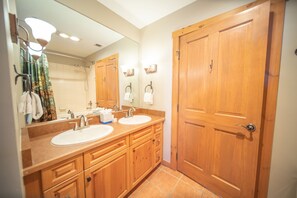 A bathroom with wooden cabinets, two sinks, and a large mirror.