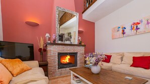 Una sala de estar con chimenea de ladrillo, un sofá, una mesa de centro y un cuadro en la pared.