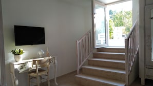 A staircase leading to an upper floor, a white desk with a chair, a potted plant, and a flat-screen TV mounted on the wall. - Romantic Trullo with Pool: Entire Private Property❣️ (Alberobello)