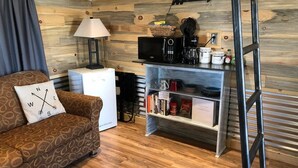 Un salon confortable avec un canapé, une machine à café et une bibliothèque.