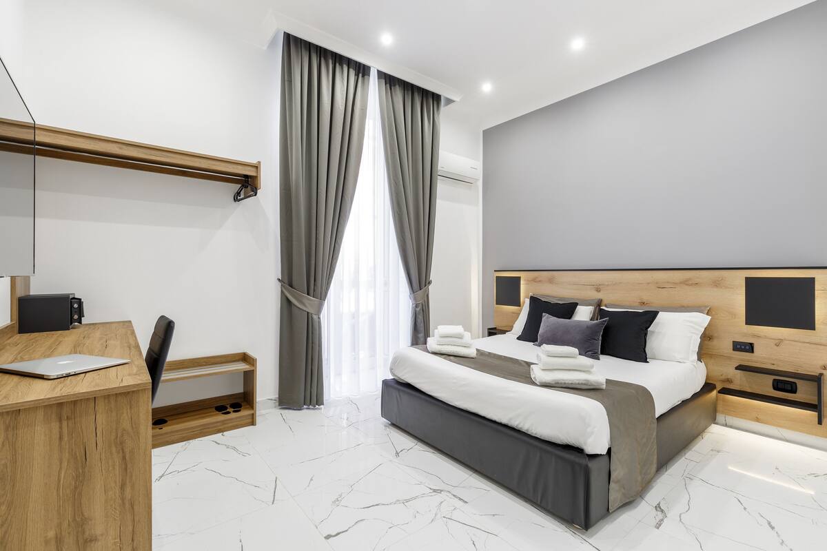 A modern bedroom with a large bed, a desk, and a chair.