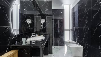 Ein modernes Badezimmer mit einem schwarzen Marmor-Waschtisch, einem weißen Waschbecken und einem Bidet.