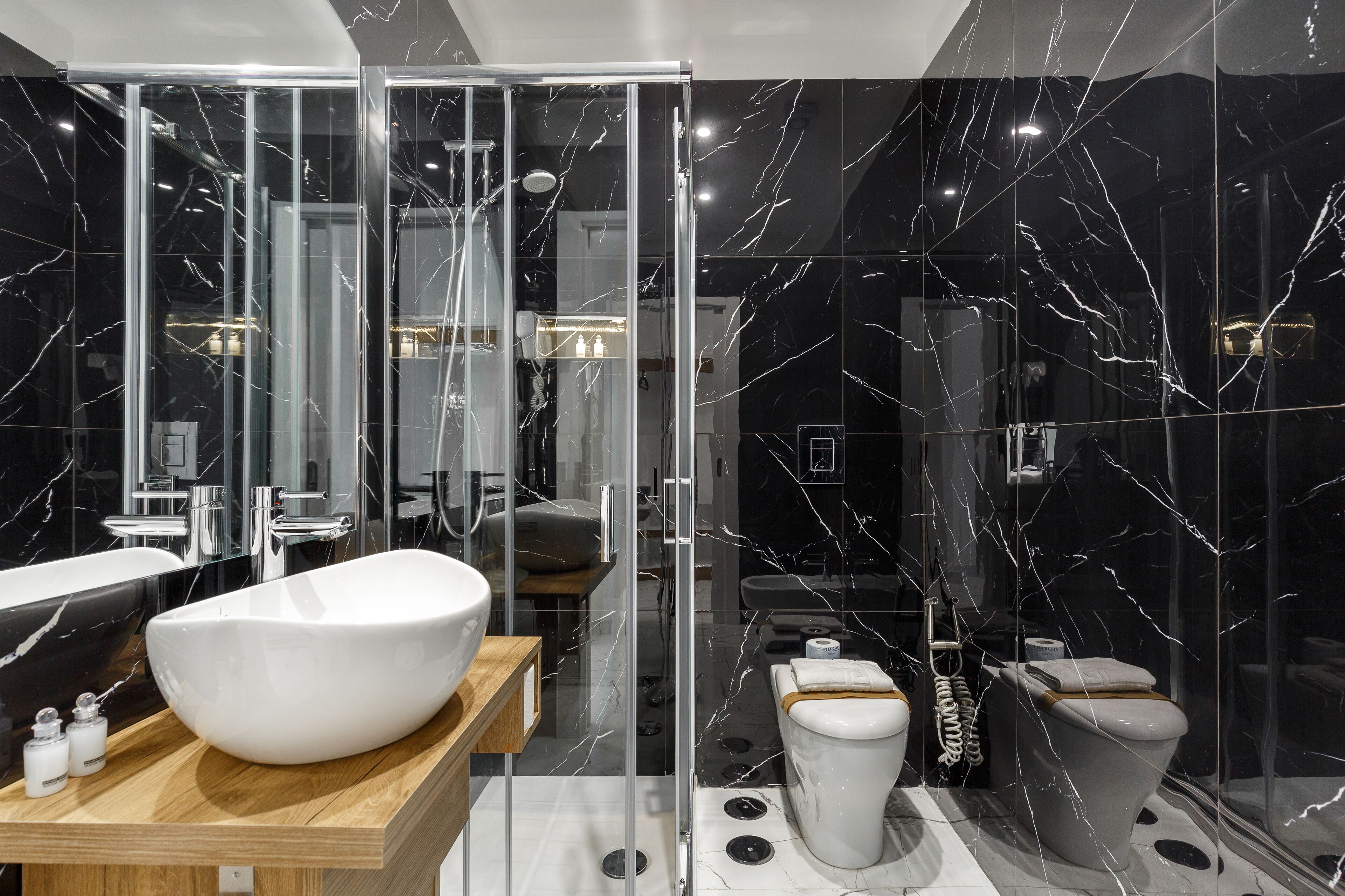 Un baño moderno con un lavamanos blanco de diseño, ducha envuelta en vidrio y un inodoro con función bidé.