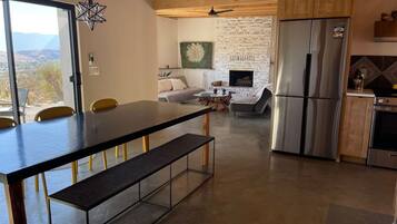 A modern kitchen with a large refrigerator, a dining area with a bench, and a fireplace.