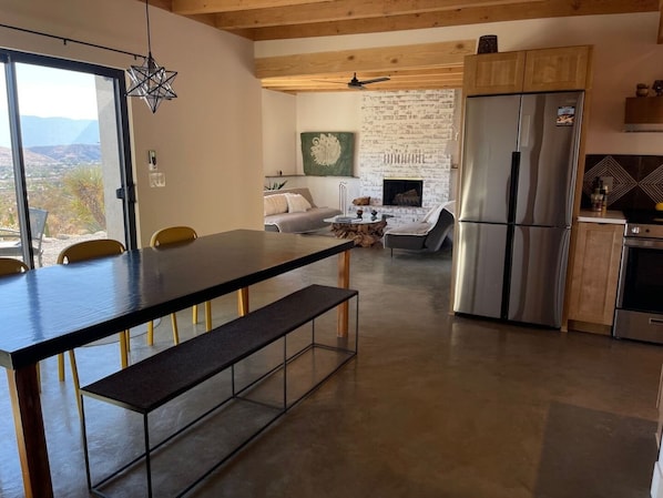 Una cocina moderna con un refrigerador grande, un área de comedor con un banco y una chimenea.