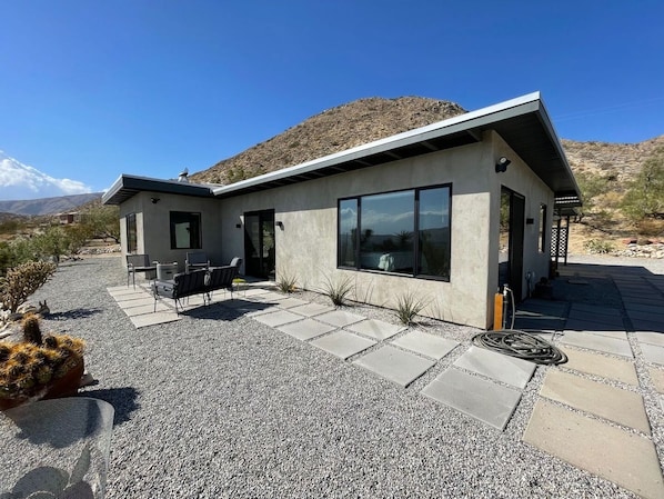 Une maison moderne dotée d’un patio, d’un espace salon extérieur et offrant une vue sur le désert.