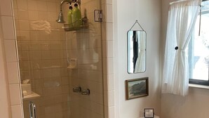 Une salle de bain avec une douche à parois de verre, des toilettes et un lavabo.