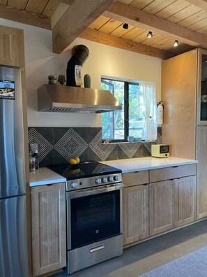 Une cuisine moderne équipée d’une cuisinière et d’un four intégrés, ainsi que d’une fenêtre avec des rideaux.