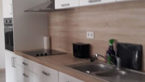 Une cuisine moderne avec des armoires blanches, un plan de travail en bois et des appareils électroménagers en acier inoxydable.