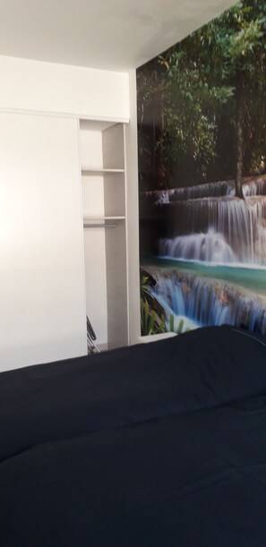 Un dormitorio con una cama, un armario blanco y un mural de una cascada.