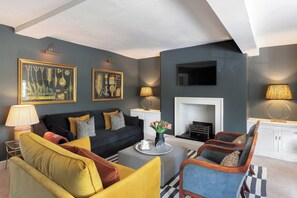A modern living room with a sofa, armchairs, a coffee table, and artwork on the walls.