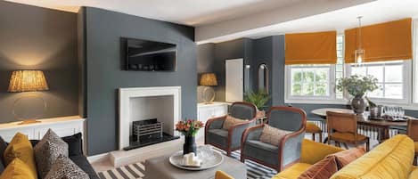 A modern living room with a fireplace, comfortable seating, and a dining area.