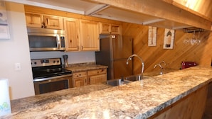 A kitchen with granite countertops, wooden cabinets, stainless steel appliances, and a built-in wine rack.