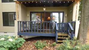 A building with a covered outdoor area, a wooden staircase, and a small garden with hydrangeas and other plants.