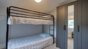 Un lit superposé avec un matelas matelassé, une armoire avec des portes coulissantes et un luminaire au plafond.