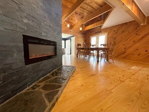 Una habitación amplia con chimenea de piedra, mesa de comedor de madera y sillas.