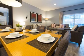 Relax in the spacious living room with a dining table set for a meal, comfortable seating area, and artworks on the wall.