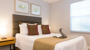 Una habitación de hotel con una cama, una mesita de noche, una lámpara y una ventana con persianas.