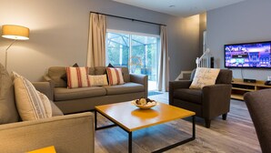 Una sala de estar moderna con un sofá, sillones, una mesa de centro y un televisor.