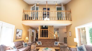 Ein geräumiger Wohnbereich mit hoher Decke, einer Holztreppe und einem Balkon.