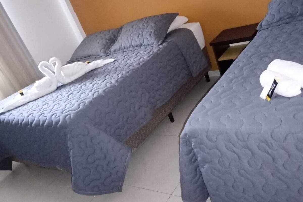 Dos camas individuales con ropa de cama gris y toallas blancas.