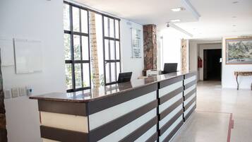 Uma receção com design moderno, uma janela ampla e um quadro de informações fixado na parede.