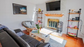 Una sala de estar con chimenea, un sofá, una mesita de centro y un televisor montado en la pared.