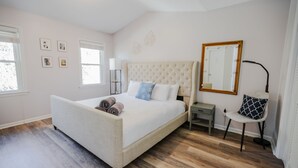 Un dormitorio con una cama grande, mesitas de noche, una silla y un espejo.