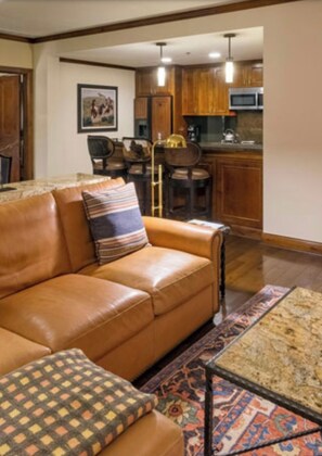 Relax in this inviting living room with a leather sofa, coffee table, and kitchen area.
