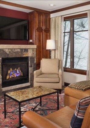 Relax in this inviting living room with a fireplace, comfortable seating, and a large window.