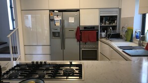 Une cuisine moderne équipée d’un réfrigérateur en acier inoxydable, d’un four encastré et d’une cuisinière à gaz.