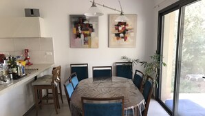 Un espace repas moderne avec une table ronde, des chaises recouvertes d’un tissu bleu et des œuvres d’art abstraites accrochées aux murs.