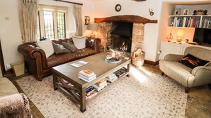 A cozy living room with a fireplace, leather sofa, and a bookshelf. - The Small House (Cheltenham)