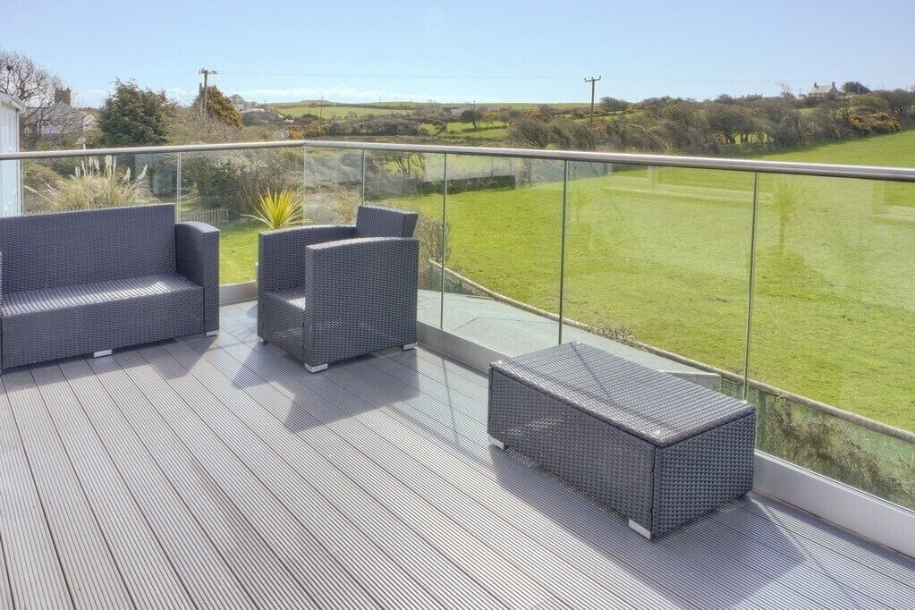 A balcony with wicker furniture and a view of a green field.