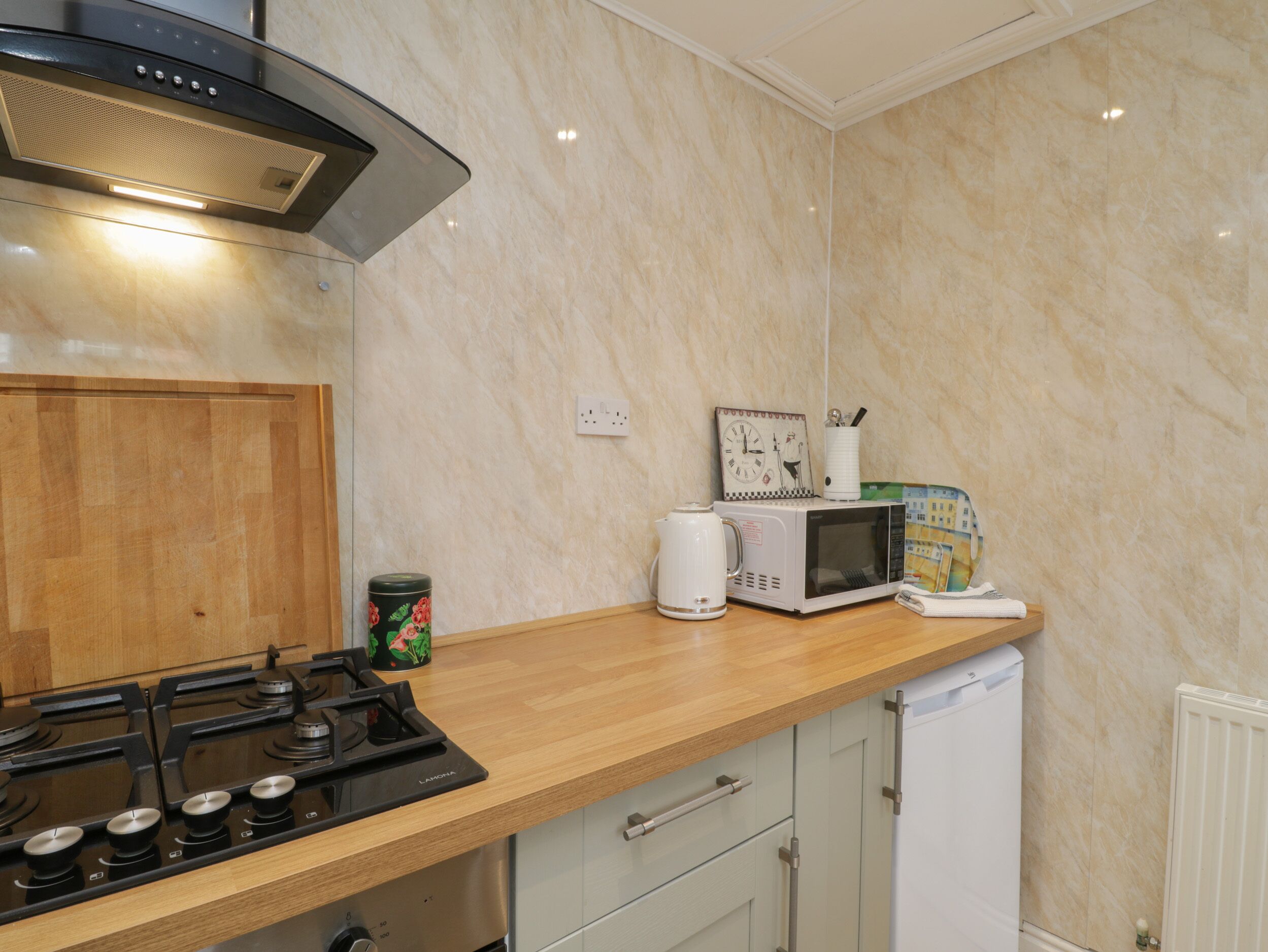 A modern kitchen with a gas stove, microwave, and a small refrigerator.