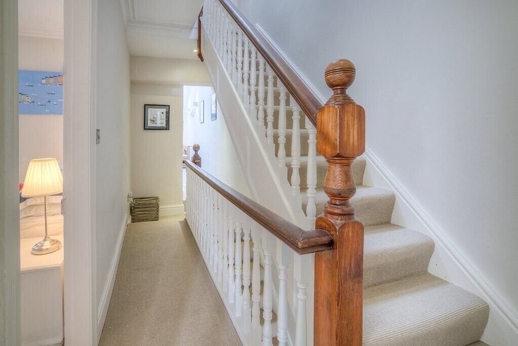 Un escalier avec une rampe en bois et des balustres blanches.