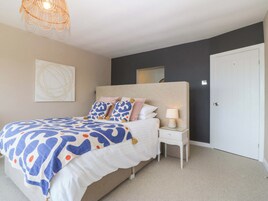 Un dormitorio con cama, mesita de noche, lámpara y una puerta.